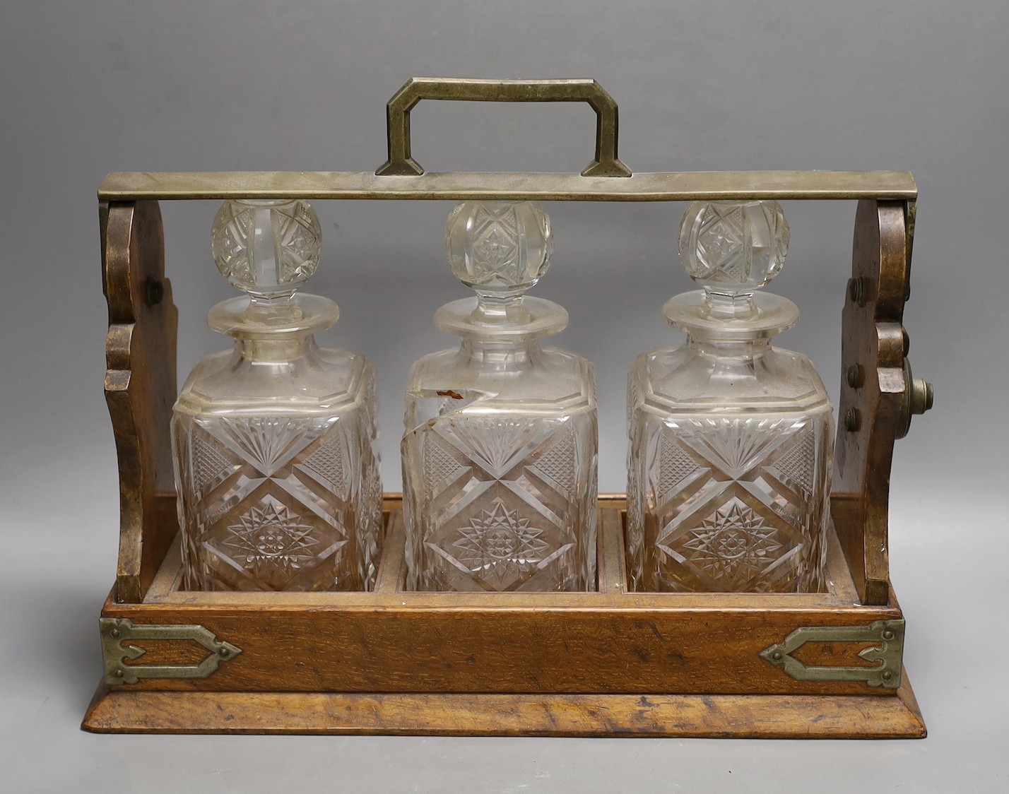 A Victorian Betjemann’s patent oak cased three bottle tantalus (a.f.), 42cms wide at base